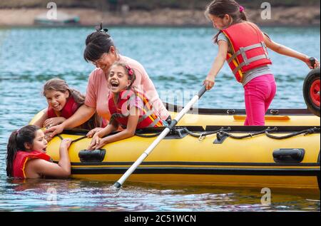 LAGO TARNITA, CLUJ COUNTY, ROMANIA - SETTEMBRE 09 2013 Ragazze da una comunità socialmente svantaggiata in giubbotti di salvataggio rosso e giallo gommone su Foto Stock