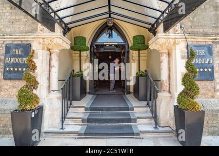 Ian, uno dei dirigenti, pulisce le maniglie delle porte anteriori del Randolph Hotel, Oxford, pronto per riaprire dopo il blocco Covid-19 il 4 luglio 2020 Foto Stock