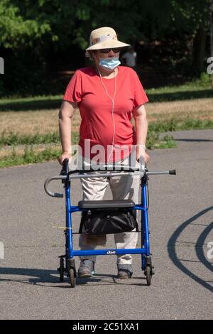 Una donna anziana in un cappello di paglia cammina intorno al lago nel Parco di Kissena, Flushing, New York. Foto Stock