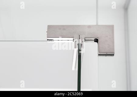 cerniere in vetro per il bagno, primo piano di accessori incernierati di divisori trasparenti sulla parete bianca vista frontale. Foto Stock