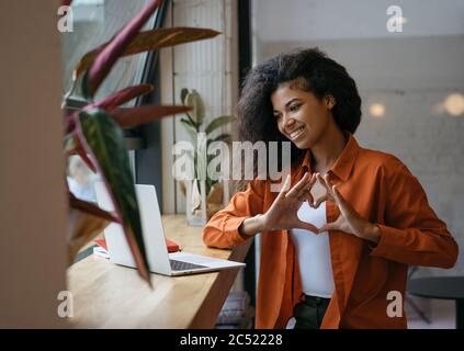 Comunicazione blogger riuscita con gli abbonati online, in diretta streaming, video chat. Bella donna afroamericana che usa un computer portatile Foto Stock