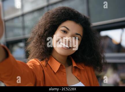 Primo piano ritratto di giovane bella donna afroamericana che prende selfie sul telefono cellulare. Video in streaming con influencer emotivo Foto Stock