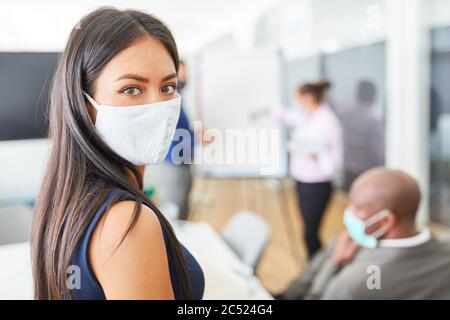 Giovane donna di affari che indossa una maschera facciale a causa di Covid-19 e corona virus che dà una presentazione in ufficio Foto Stock