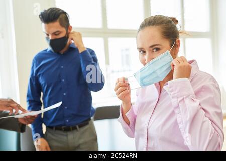 Due imprenditori con protezione per bocca e naso in ufficio a causa di Covid-19 e coronavirus pandemia Foto Stock