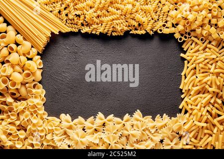 Cumulo di pasta cruda o maccheroni di vario tipo e forme con spazio di copia per il testo. Vista dall'alto. Foto Stock