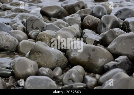 Sfondi naturali e texture di ciottoli, pietre e rocce sulla spiaggia nel Galles del Sud. Primo piano dei diversi modelli di dimensioni. Foto Stock