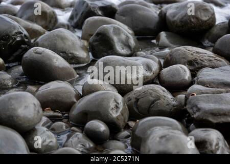 Sfondi naturali e texture di ciottoli, pietre e rocce sulla spiaggia nel Galles del Sud. Primo piano dei diversi modelli di dimensioni. Foto Stock