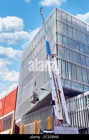Montreal, Canada - Giugno, 2018: Una gru e lavoratori su una piattaforma di ascensore che puliscono le finestre di un edificio a Montreal, Quebec, Canada. Foto Stock