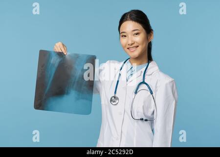 Medico femminile in un cappotto medico tiene un x-ray nel suo sorriso mano Foto Stock