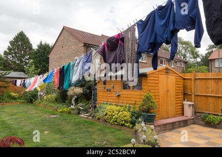Lavaggio appeso su lunga linea che asciuga nel tempo ventoso e gusty. La lunghezza completa del mio giardino ha preso con l'asciugatura di lavaggio e soffiando intorno alla fine Foto Stock