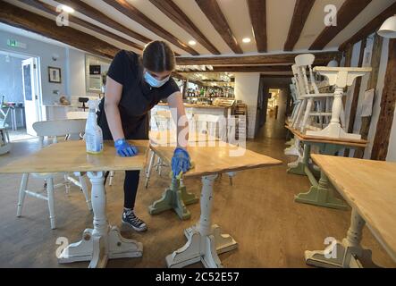 Il membro dello staff Megan Campon, 20 anni, presso la sala da tè del vincitore a Finchingfield, Essex, pulisce i tavoli e le sedie pronti per l'impilamento, prima della riapertura dei locali per i clienti seduti il 4 luglio, poiché ulteriori restrizioni di blocco del coronavirus sono state abolite in Inghilterra. Foto Stock