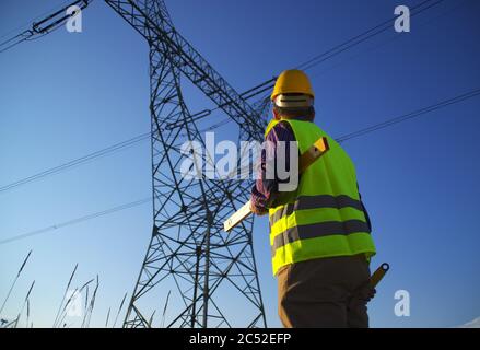 Tecnico durante l'ispezione della linea di alimentazione. Elettricista al lavoro. Produzione e fornitura di energia da centrali elettriche. Foto Stock