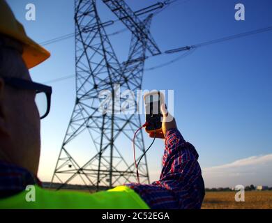 Durante l'ispezione dell'infrastruttura della linea elettrica, è possibile eseguire un'ispezione con un manometro. Elettricista al sondaggio. Misurazione della rete energetica. Foto Stock