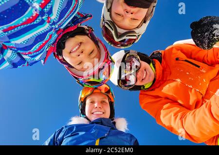 Gruppo di bambini in maschera da sci e caschi si affacciano insieme in piedi su cielo blu Foto Stock