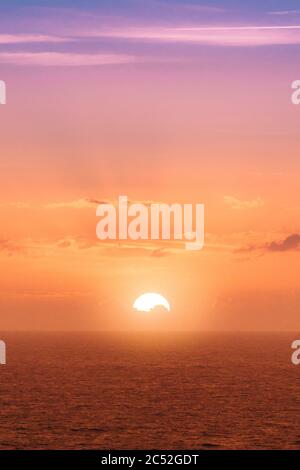 Immagine verticale di un affascinante tramonto dietro una carta da parati perfetta per il mare Foto Stock