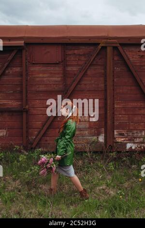 Donna che cammina all'aperto portando un mazzo di fiori lilla Foto Stock