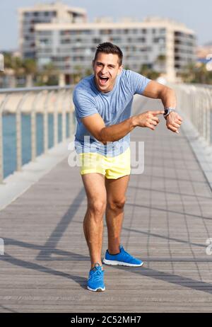 Atleta uomo verifica risultati fitness su sport tracker braccialetto dopo la sessione di allenamento Foto Stock