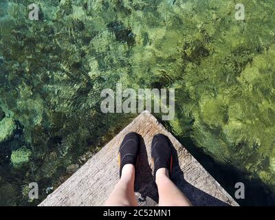 Donna in piedi su un molo pronto a tuffarsi in mare, Malta Foto Stock