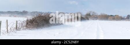 Una neve frizzante batte il Regno Unito con tempesta Emma. Un piccolo borgo medievale chiamato Hoo è mostrato una vista attraverso i campi e le scuderie Foto Stock