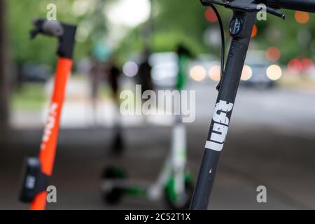 Primo piano di uno scooter elettrico Lyft con moto da competizione Jump and Lime sfocato sullo sfondo. Foto Stock