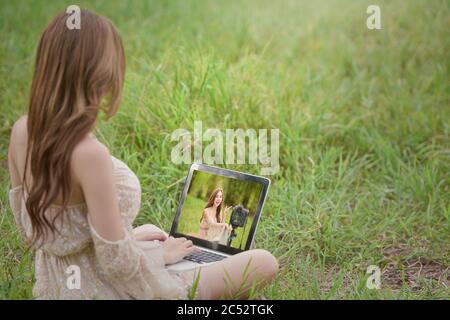 Donna seduta in un campo di revisione vlogging filmare, Thailandia Foto Stock