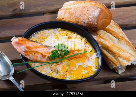 Deliziosa zuppa di salmone cremosa in ciotola nera servita con baguette Foto Stock