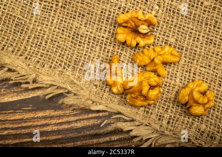 Noci pelate sfuse su un tavolo di legno coperto di tela ruvida. Dieta sana. Dieta di idoneità. Primo piano Foto Stock