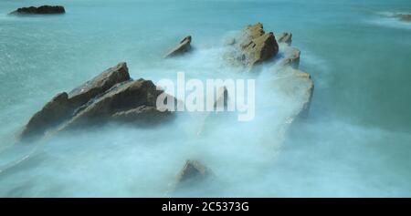 Rocce circondate da onde di mare sfocate sulla costa nord del Devon, Inghilterra Foto Stock