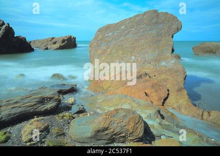 Rocce circondate da onde di mare sfocate sulla costa nord del Devon, Inghilterra Foto Stock