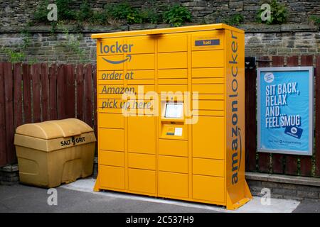 Amazon Locker con testo Ciao il mio nome è Kati sulla piattaforma alla stazione ferroviaria di Marple. Recinto e muro di pietra sullo sfondo Foto Stock