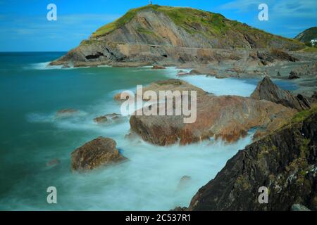 Rocce circondate da onde di mare sfocate sulla costa nord del Devon, Inghilterra Foto Stock