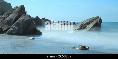 Rocce circondate da onde di mare sfocate sulla costa nord del Devon, Inghilterra Foto Stock