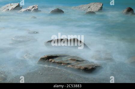 Rocce circondate da onde di mare sfocate sulla costa nord del Devon, Inghilterra Foto Stock