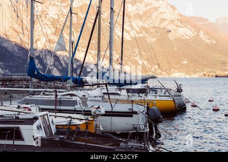 Il dorso di yacht ormeggiato in porto durante la mattinata arancione sulla superficie del lago di Garda in Italia Foto Stock