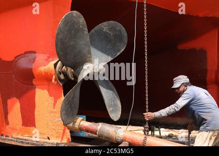 Un lavoratore che lavora su una nave in un cantiere di rottura a keraniganj durante la crisi del coronavirus.a seguito del rilassamento delle restrizioni del covid-19, i lavoratori nell'industria di demolizione e costruzione della nave del Bangladesh optano per riprendere il lavoro con la speranza di assicurare la stabilità finanziaria dopo essere stati lasciati con quasi nessun lavoro, che porta a una crisi finanziaria estrema. Foto Stock