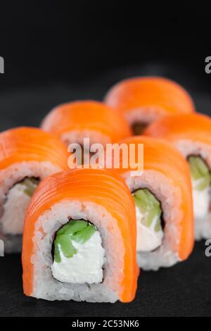 Porzione di fresco sushi roll philadelphia su sfondo nero Foto Stock