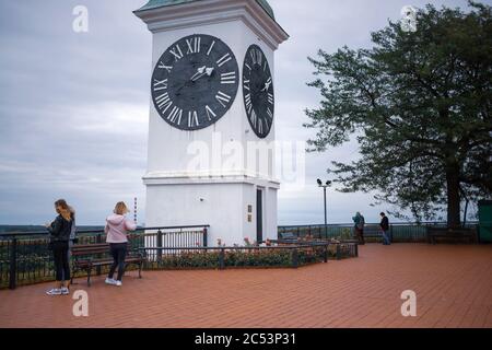 Novi Sad, Serbia, 23 giugno 2020: Visitatori in un punto di vista della Fortezza di Petrovaradin accanto ad una Torre dell'Orologio Foto Stock