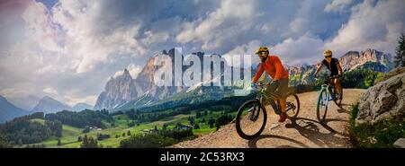 Coppia in bicicletta elettrica, passeggiate in mountain trail. Donna e uomo in bicicletta nel paesaggio delle Dolomiti. Ciclismo e-mtb enduro trail trac Foto Stock