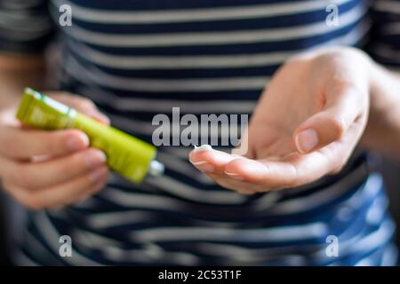 Le mani della donna usando un tubo di unguento. Applicare una crema emolliente nel trattamento e idratazione della pelle. Concetto di cura della pelle. Foto Stock
