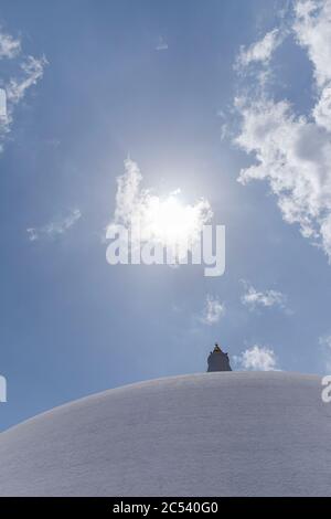 Dagoba bianco contro un cielo blu e sole, tetto a cupola di un tempio in Sri Lanka Foto Stock