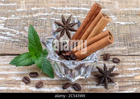 Chicchi di caffè e spezie aromatiche su sfondo di legno. Foto Stock