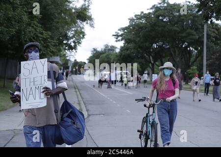 Un uomo visto tra la folla di manifestanti BLM che sostengono un poster con gli scritti dicono i loro nomi. Le vite nere contano le proteste Foto Stock