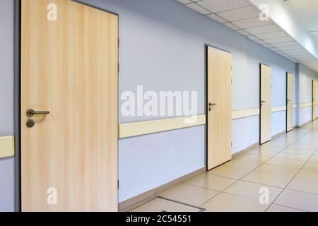 Un lungo corridoio con molte porte in ufficio o in clinica Foto Stock
