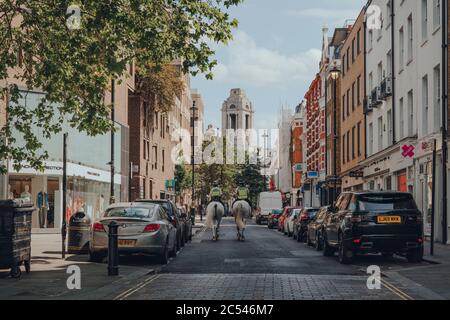 Londra, UK - 13 giugno 2020: Le guardie della polizia a cavallo pattugliano la strada vuota in Covent Garden, un'area turistica tipicamente trafficata a Londra con un sacco di sho Foto Stock