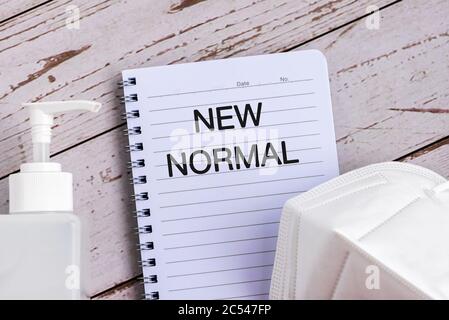 Nuovo testo normale su note pad, maschera chirurgica viso e igienizzatore Foto Stock