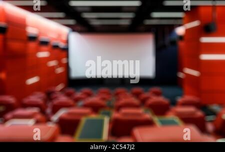 Panorama di una sala cinematografica vuota come sfondo creativo e astratto sfocato. Auditorium con design contemporaneo rosso con schermo. Cinema moderno i Foto Stock