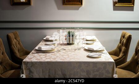 Tavolo in ristorante urbano o bar closeup. Interni classici di un'accogliente caffetteria con un tavolo servito contro le pareti. Illuminazione intima e piacevole. Foto Stock