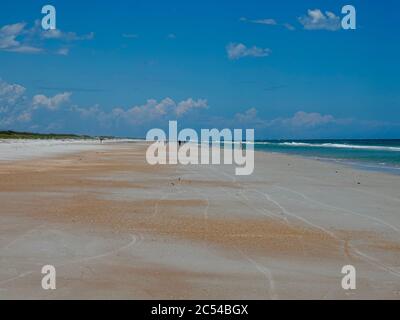 Persone, viste lontane, opportunamente distanziate su un'ampia distesa di spiaggia lungo l'Oceano Atlantico all'Anastasia state Park, St. Augustine, Florida, USA. Foto Stock