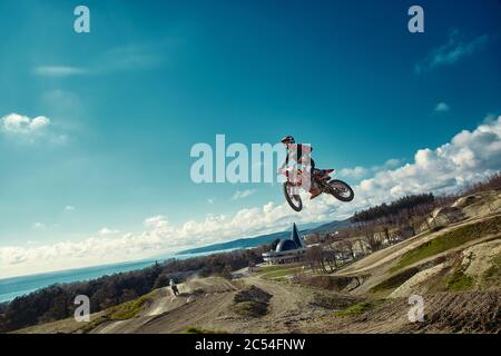 racer in mountain bike partecipa alla gara di motocross, decollo e salta su trampolino, contro il cielo blu. Primo piano. Concetto di riposo estremo Foto Stock