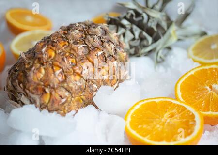 Arance di ananas e limoni giacciono sul ghiaccio. Agrumi su ghiaccio Foto Stock